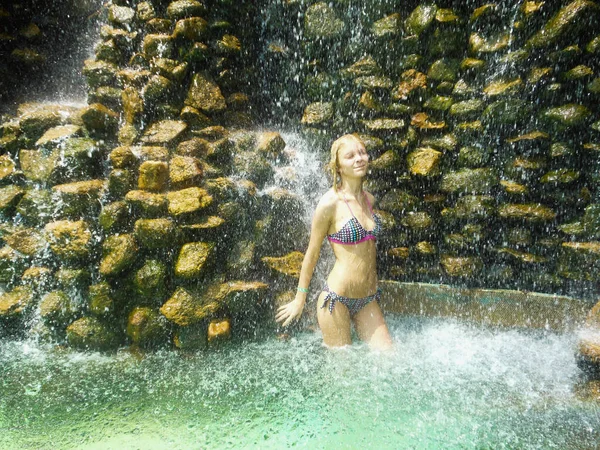 Fiatal szőke lány fürdőruhában pózol egy vízesésben — Stock Fotó