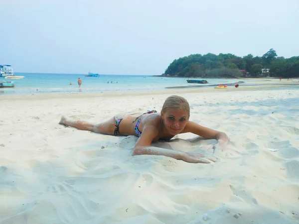 Giovane abbronzata donna magra in costume da bagno è sdraiato sulla sabbia sulla spiaggia. l'oceano dietro, thailandia, abbronzatura, vacanza — Foto Stock