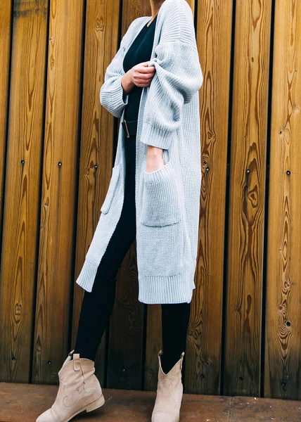 Junge Frau in langem grauen Pullover und schwarzen Nylonstrumpfhosen-Stiefeln gegen eine zypriotische Wand — Stockfoto