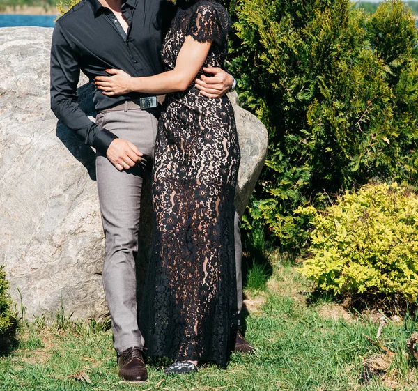 Jeune couple femme dans une longue robe élégante en dentelle noire homme en pantalon et chemise. histoire d'amour extérieur, tendresse, câlins — Photo