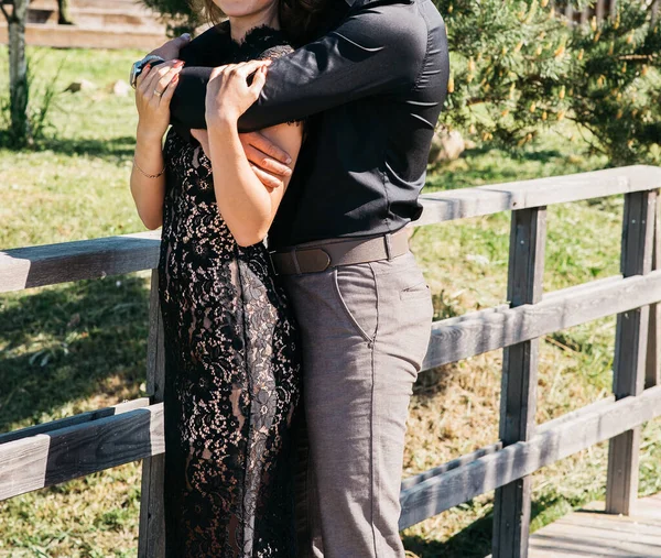 Jovem mulher casal em um homem vestido preto rendas longa elegante em calças e camisa. história de amor ao ar livre, ternura, abraços — Fotografia de Stock