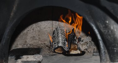 Pişirmek için ateş yakan Rus fırını. Ahşap yanan kömür ısısı