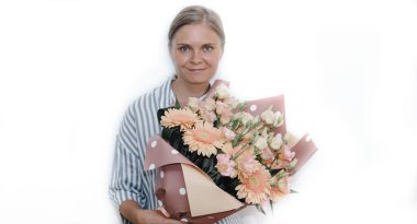 Çizgili mavi bluzlu genç kadın kocaman bir buket turuncu Gerbera gül çiçeği tutuyor. Kadına doğum günü hediyesi. 