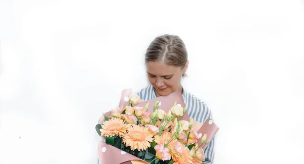 Jonge vrouw in een gestreepte blauwe blouse houdt een enorm boeket van oranje gerbera roos bloemen. verjaardagscadeau aan de vrouw. — Stockfoto