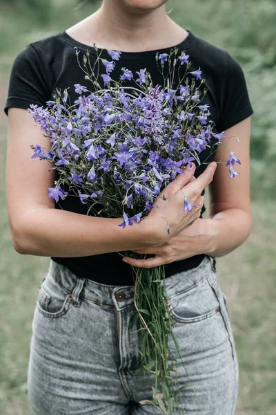 Молодая женщина с длинными волосами держит в руках букет полевых цветов голубого цвета. сельские луга, ферма — стоковое фото