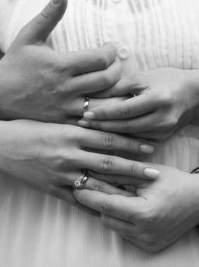 Elleri bükülmüş genç insanlar. Nişan yüzüklerinin üzerinde beyaz altından elmaslar var. Evlilik töreni.