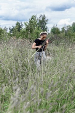 Kafasında papatya çelengi olan genç bir kadın. Güneşin altında çimlerin üzerinde. 