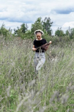 Kafasında papatya çelengi olan genç bir kadın. Güneşin altında çimlerin üzerinde. 