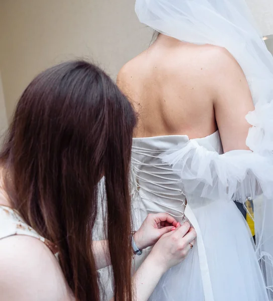 gathering the bride wedding preparation bridesmaid helps to put on a dress with a corset and lacing