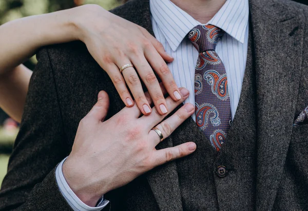 신부들은 그들의 향기 로운 꽃다발에 흰 황금 다이아몬드가 달린 우아 한 결혼반지를 끼고 손을 잡고 있다 — 스톡 사진