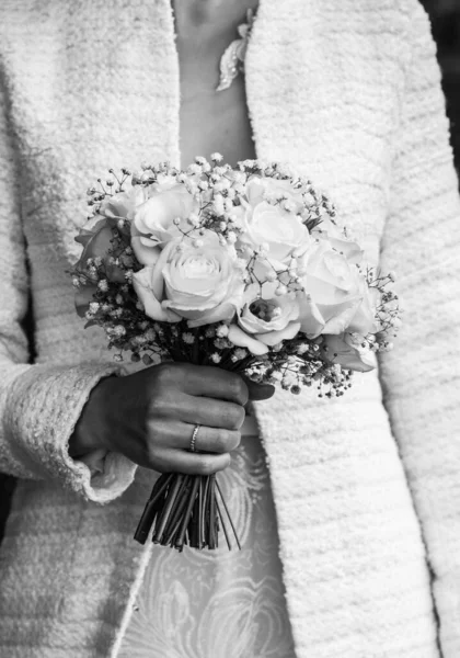 Bruiden hand met een elegante trouwring met witgouden diamanten op een boeket pioenen — Stockfoto