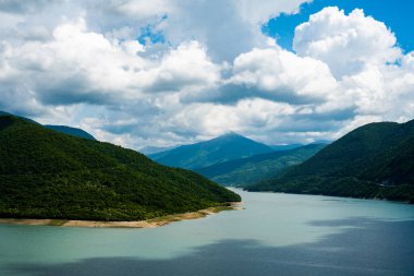 Berrak bir gökyüzü ve dağ tepelerinin arka planında mavi turkuaz berrak su ile dağ gölü
