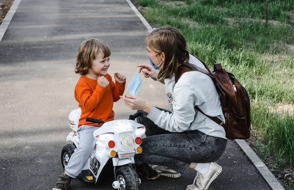 Anya felvesz egy orvosi védőmaszkot egy sétáló gyereknek. Koronavírus-világjárvány elleni védelem Megelőzés Levegőszennyezés koncepciója Járványvírus tünetei. — Stock Fotó