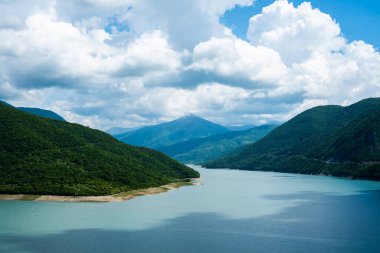 Berrak bir gökyüzü ve dağ tepelerinin arka planında mavi turkuaz berrak su ile dağ gölü