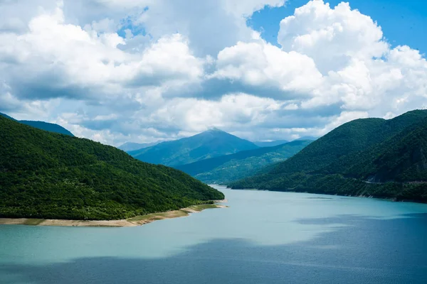 Berrak bir gökyüzü ve dağ tepelerinin arka planında mavi turkuaz berrak su ile dağ gölü