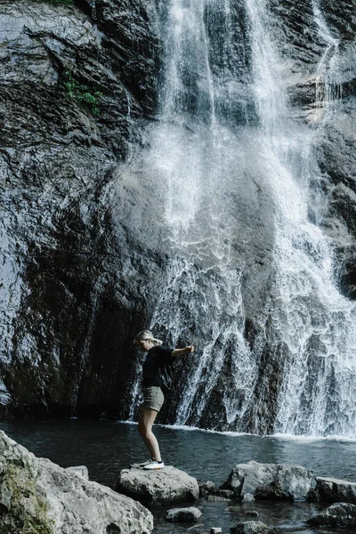 Młoda kobieta na tle górskiego wodospadu z kucykiem — Zdjęcie stockowe