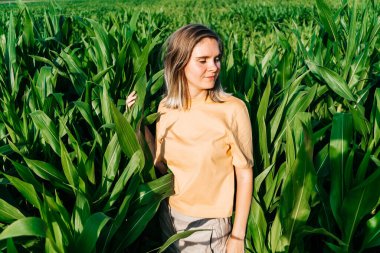 Sarı tişörtlü, mısır tarlasında kısa saçlı genç bir kadın.