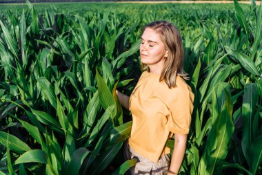 Sarı tişörtlü, mısır tarlasında kısa saçlı genç bir kadın.