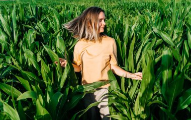 Sarı tişörtlü, mısır tarlasında kısa saçlı genç bir kadın.