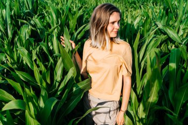Sarı tişörtlü, mısır tarlasında kısa saçlı genç bir kadın.