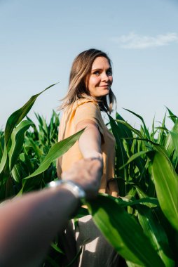 Sarı tişörtlü, mısır tarlasında kısa saçlı genç bir kadın.