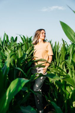 Sarı tişörtlü, mısır tarlasında kısa saçlı genç bir kadın.