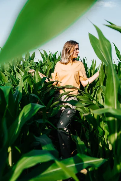 Sarı tişörtlü, mısır tarlasında kısa saçlı genç bir kadın.