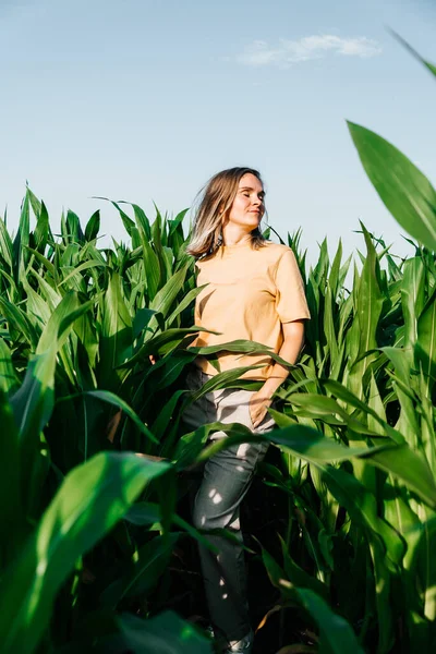 Sarı tişörtlü, mısır tarlasında kısa saçlı genç bir kadın.