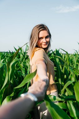 Sarı tişörtlü, mısır tarlasında kısa saçlı genç bir kadın.