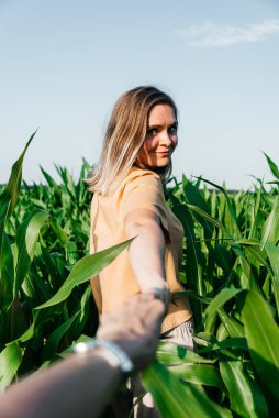 Sarı tişörtlü, mısır tarlasında kısa saçlı genç bir kadın.