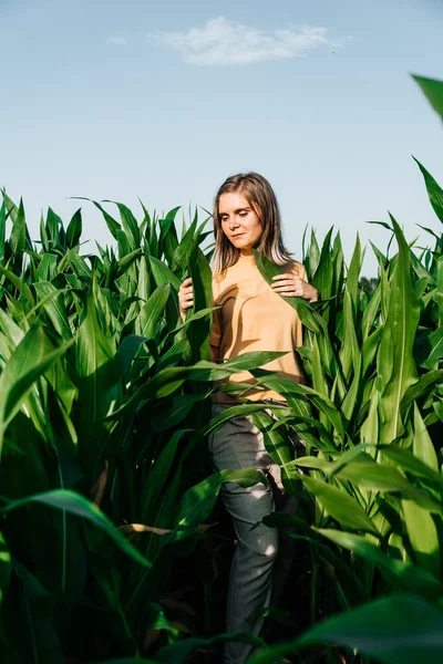 Sarı tişörtlü, mısır tarlasında kısa saçlı genç bir kadın.