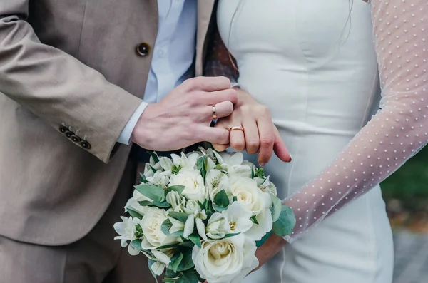 Gelinler, şakayık demetinde beyaz altın elmaslarla zarif bir alyansla el ele tutuşurlar.