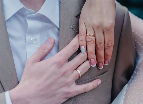 신부들은 그들의 향기 로운 꽃다발에 흰 황금 다이아몬드가 달린 우아 한 결혼반지를 끼고 손을 잡고 있다 — 스톡 사진