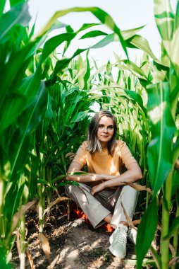 Sarı tişörtlü, mısır tarlasında kısa saçlı genç bir kadın.