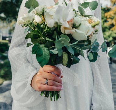 Evlilik yüzükleri takan gençlerin elleri. Düğün günü detayları. Kala çiçekleri. yeni evli eşler damat ve gelin