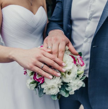 Kutuda beyaz altın alyanslar ve bir buket narin gül ve yeşillik.