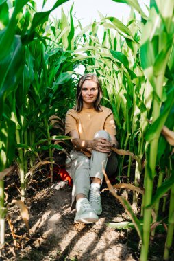 Sarı tişörtlü, mısır tarlasında kısa saçlı genç bir kadın.