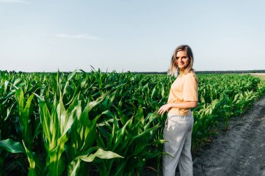 Sarı tişörtlü, mısır tarlasında kısa saçlı genç bir kadın.