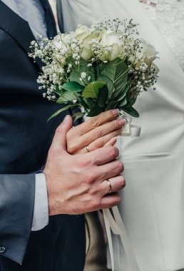 Evlilik yüzükleri takan gençlerin elleri. Düğün günü detayları. Kala çiçekleri. yeni evli eşler damat ve gelin