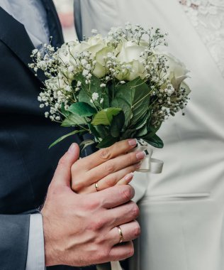 Evlilik yüzükleri takan gençlerin elleri. Düğün günü detayları. Kala çiçekleri. yeni evli eşler damat ve gelin