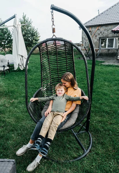 Mamma och barn rider på en rotting kokong gunga. son skakar en kvinna, skakar en sommar semester i naturen — Stockfoto