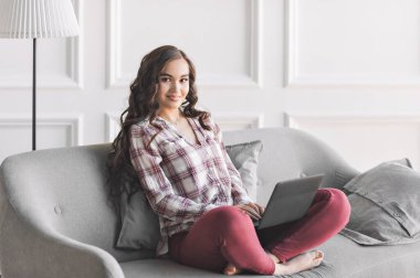 Evde dizüstü bilgisayar kullanan genç bir kadın. Bir öğrenci bilgisayarda çalışır. Serbest, TEKNOLOJİ, online alışveriş, ev işleri, online eğitim. Uzaklık öğrenimi.