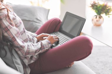 Evde dizüstü bilgisayar kullanan genç bir kadın. Bir öğrenci bilgisayarda çalışır. Serbest, TEKNOLOJİ, online alışveriş, ev işleri, online eğitim. Uzaklık öğrenimi.