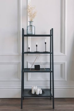 Konforlu gerçek bir ev dekorasyonu, modern İskandinav iç mimarisinde mumları olan siyah bir kitaplık..