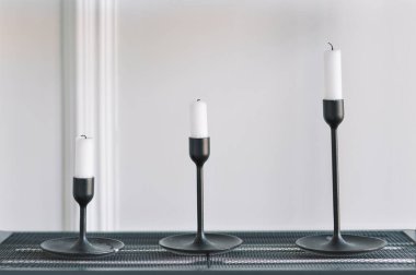 Konforlu gerçek ev dekorasyonu, modern İskandinav iç mimarisinin siyah rafında beyaz mumlar..