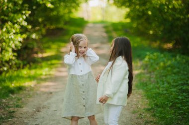 Küçük kızlar parkta eğleniyor. Yazın iki küçük kız parkta oynuyor. Arkadaşlık..