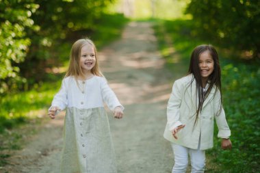 Beyazlı küçük kızlar parkta dans edip eğleniyorlar. Yazın, iki küçük kız parkta oynuyor. Arkadaşlık..