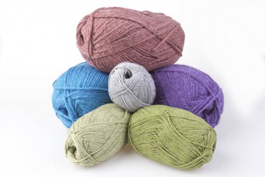 Yün elleri ile örgü için rahim. Birkaç parça piramit yığılmış. Küçük ve büyük beyaz arka planda dağınık