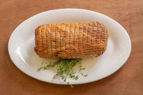 Prosciutto di maiale affumicato con timo. Intero pezzo su un piatto bianco — Foto Stock