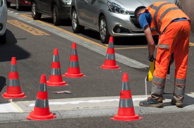 İşçiler bir Street güvenliği için turuncu koniler ile beyaz yaya yaya geçidi boyama closeup